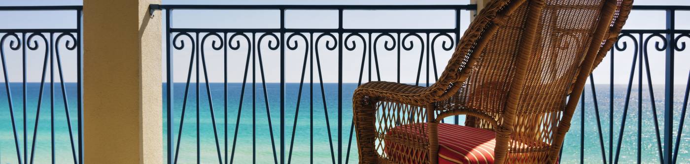 Wooden rocking chair on a deck looking over the ocean.